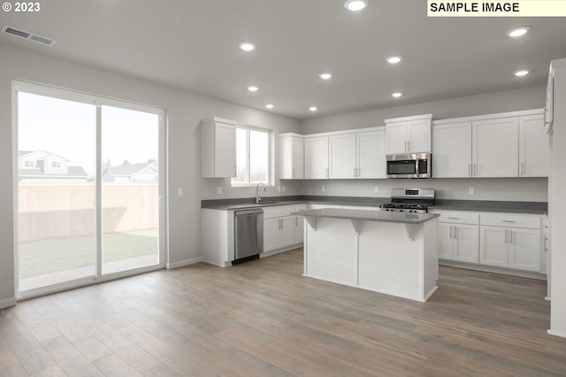 kitchen featuring stainless steel appliances, a kitchen island, sink, light hardwood / wood-style flooring, and white cabinetry