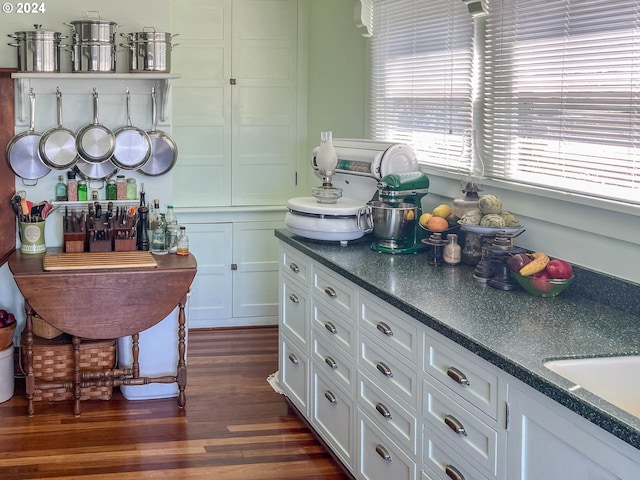 kitchen featuring dark wood-style flooring, dark countertops, a sink, and white cabinets