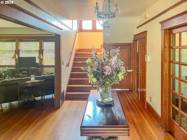 foyer entrance with baseboards, stairway, wood-type flooring, and an inviting chandelier