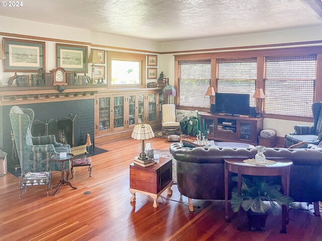 living room featuring a fireplace, a textured ceiling, and hardwood / wood-style floors