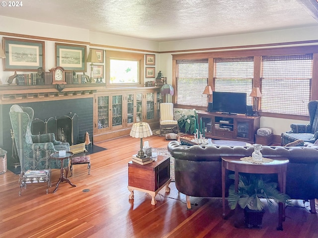 living room featuring a textured ceiling, a brick fireplace, and wood finished floors