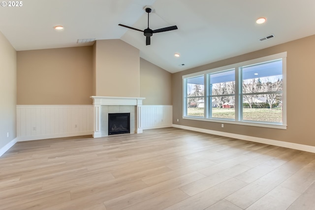 unfurnished living room featuring ceiling fan, lofted ceiling, light wood-type flooring, and a fireplace