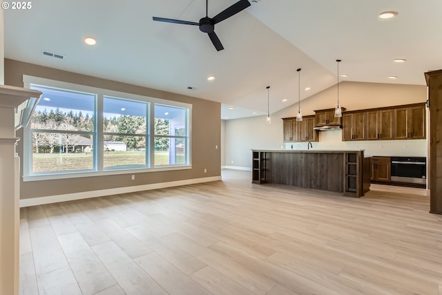 kitchen featuring a kitchen island, pendant lighting, stainless steel oven, ceiling fan, and light hardwood / wood-style floors