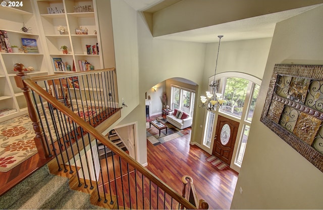 foyer with hardwood / wood-style floors, a towering ceiling, and a chandelier