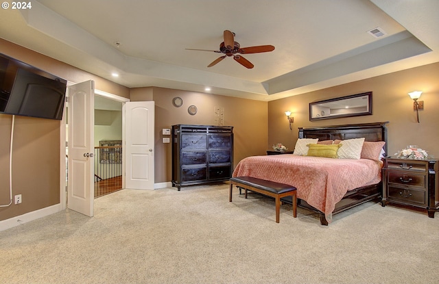 carpeted bedroom featuring a raised ceiling and ceiling fan