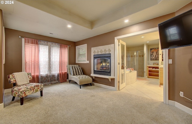 living area featuring light carpet and a tiled fireplace