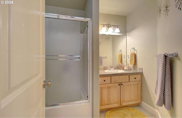 bathroom featuring tile patterned flooring, vanity, and combined bath / shower with glass door