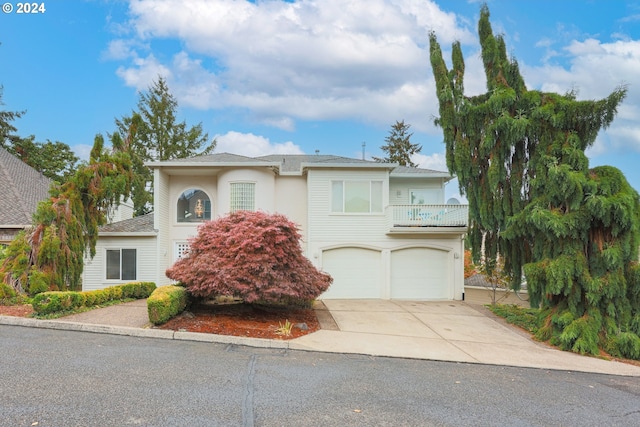 view of front of house with a garage, a balcony, concrete driveway, and stucco siding