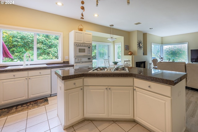 kitchen with tile counters, open floor plan, white cabinets, white appliances, and a sink