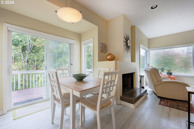 dining area with a wealth of natural light, a fireplace with raised hearth, and wood finished floors