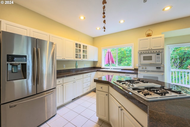 kitchen with white appliances, dark countertops, light tile patterned floors, and a healthy amount of sunlight