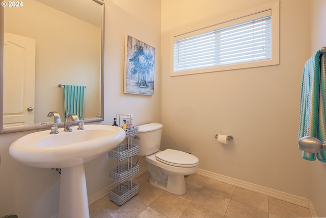 half bathroom featuring tile patterned floors, toilet, and baseboards