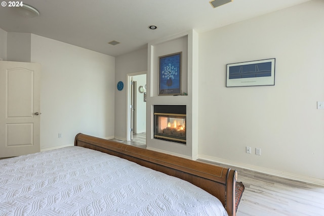 bedroom featuring a multi sided fireplace, visible vents, and baseboards