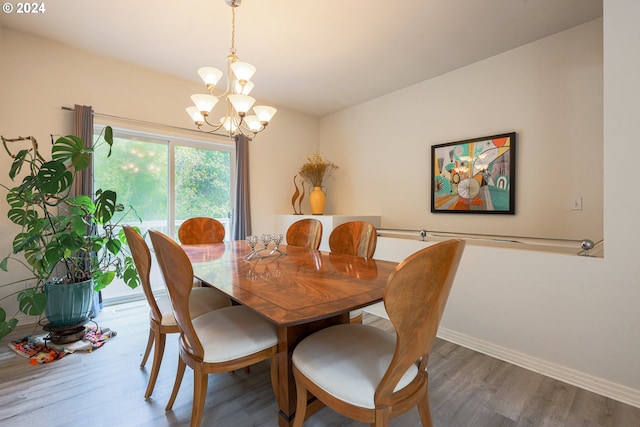 dining space with hardwood / wood-style floors and a notable chandelier