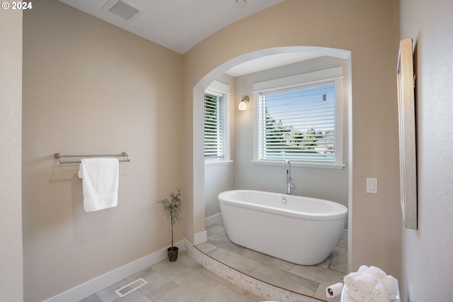 bathroom with tile patterned flooring and a bath