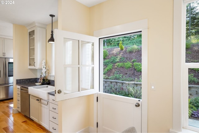 kitchen with decorative light fixtures, plenty of natural light, white cabinetry, and appliances with stainless steel finishes