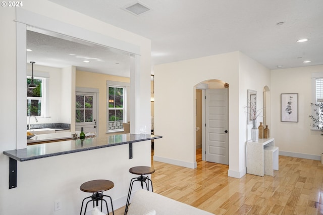 kitchen featuring a breakfast bar, light hardwood / wood-style flooring, and plenty of natural light