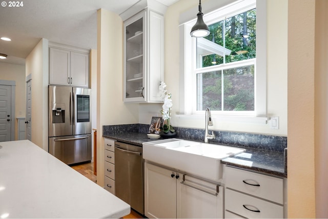 kitchen with sink, white cabinets, stainless steel appliances, and decorative light fixtures