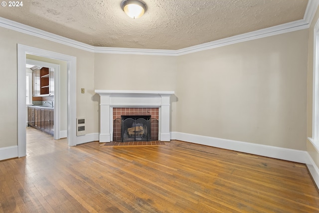 unfurnished living room featuring hardwood / wood-style flooring, sink, crown molding, and a tiled fireplace