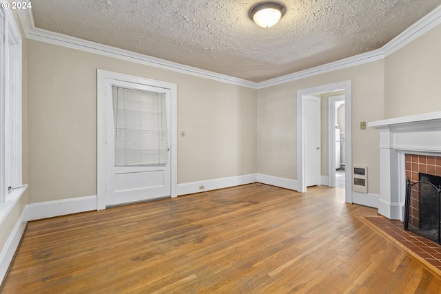 unfurnished living room with a textured ceiling, heating unit, crown molding, a fireplace, and hardwood / wood-style floors