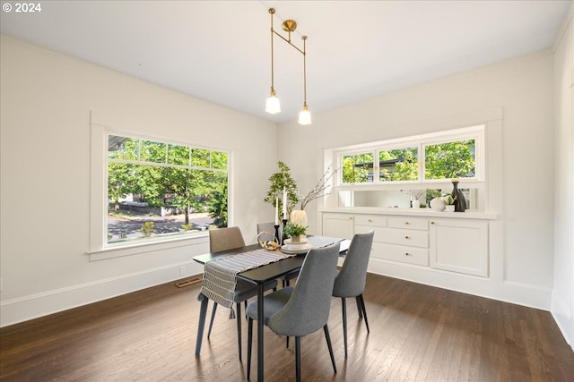 dining space with dark wood-type flooring, crown molding, and a wealth of natural light