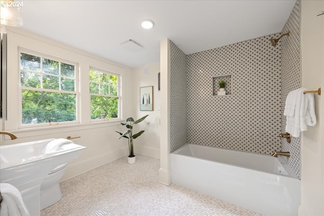 bathroom featuring toilet, tiled shower / bath combo, and tile patterned flooring