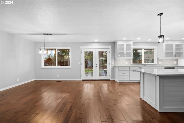 kitchen with french doors, dark hardwood / wood-style flooring, tasteful backsplash, white cabinetry, and hanging light fixtures