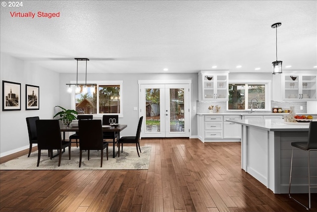 dining area featuring a textured ceiling, sink, dark wood-type flooring, and french doors