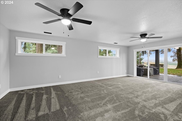 carpeted spare room featuring a textured ceiling, a wealth of natural light, and ceiling fan