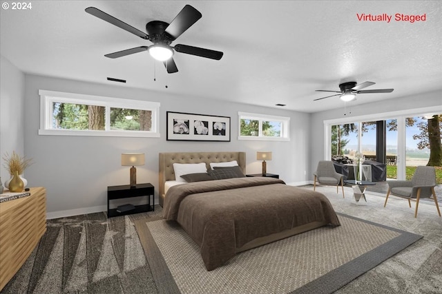 carpeted bedroom featuring ceiling fan, a textured ceiling, and multiple windows