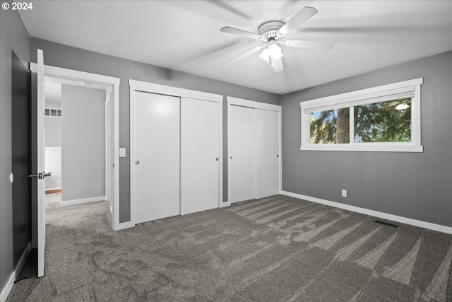 unfurnished bedroom with multiple closets, ceiling fan, and carpet