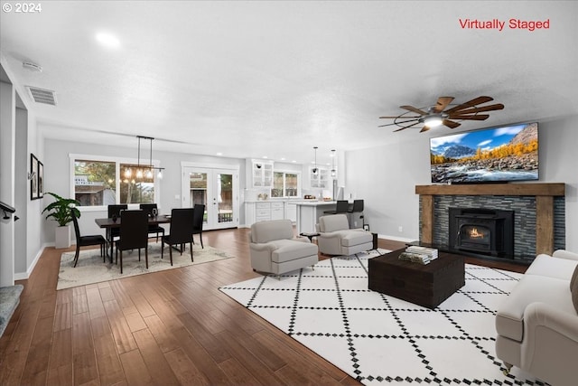 living room with a stone fireplace, ceiling fan, light hardwood / wood-style flooring, and a textured ceiling