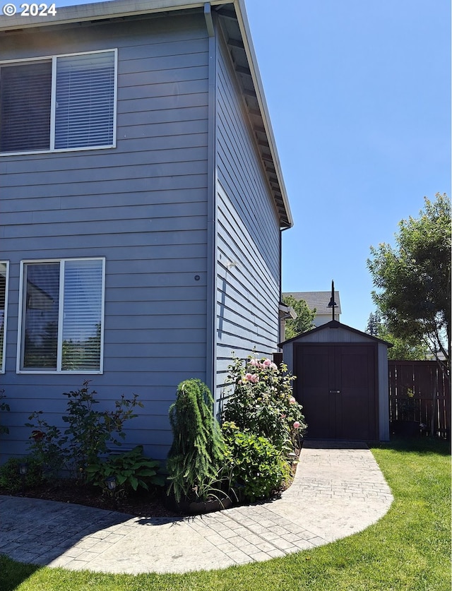 view of side of home with a storage unit and a yard