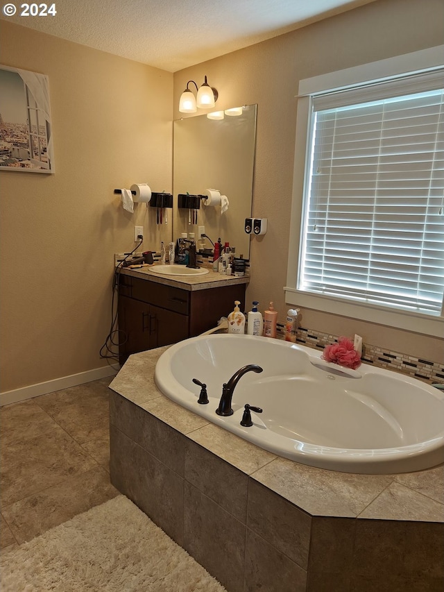 bathroom with tiled bath, a textured ceiling, and vanity