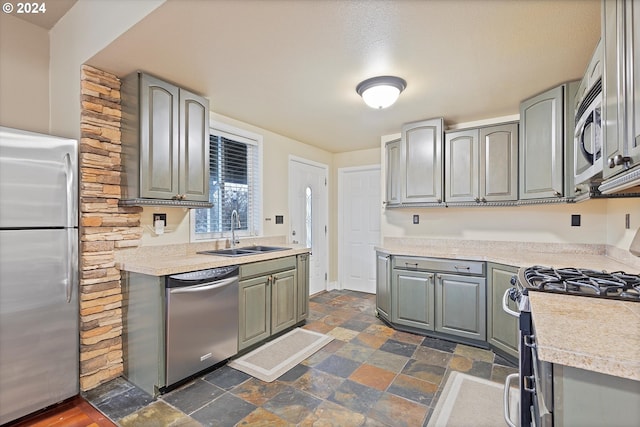 kitchen with appliances with stainless steel finishes, a textured ceiling, gray cabinets, and sink