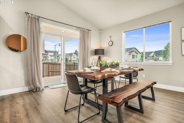 dining area with plenty of natural light, light hardwood / wood-style floors, and vaulted ceiling