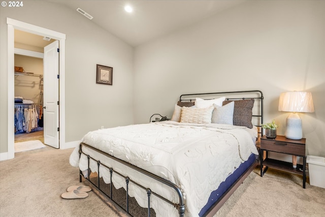 carpeted bedroom featuring a spacious closet, a closet, and lofted ceiling