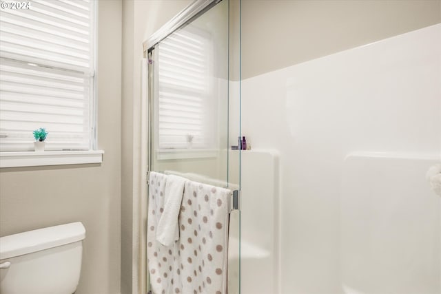 bathroom featuring toilet and a shower with door