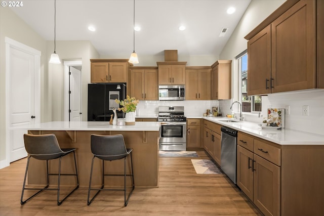 kitchen with pendant lighting, sink, stainless steel appliances, and vaulted ceiling