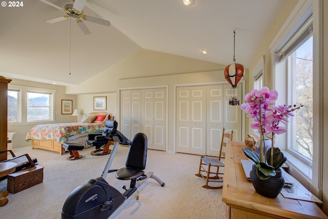 bedroom featuring multiple windows, light carpet, ceiling fan, and two closets