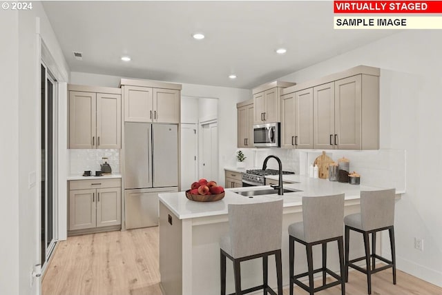 kitchen featuring kitchen peninsula, light hardwood / wood-style flooring, a kitchen breakfast bar, stainless steel appliances, and decorative backsplash