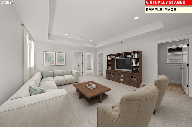 living room featuring a raised ceiling and light wood-type flooring