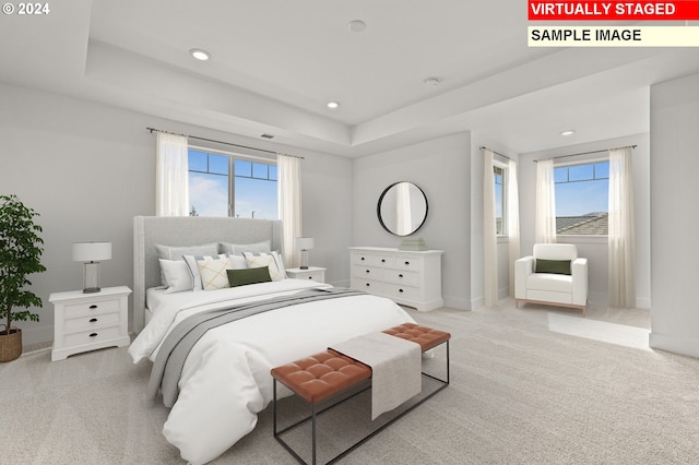 bedroom with light carpet, a raised ceiling, and multiple windows