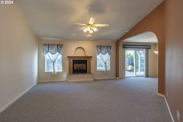 unfurnished living room featuring light carpet, vaulted ceiling, plenty of natural light, and ceiling fan