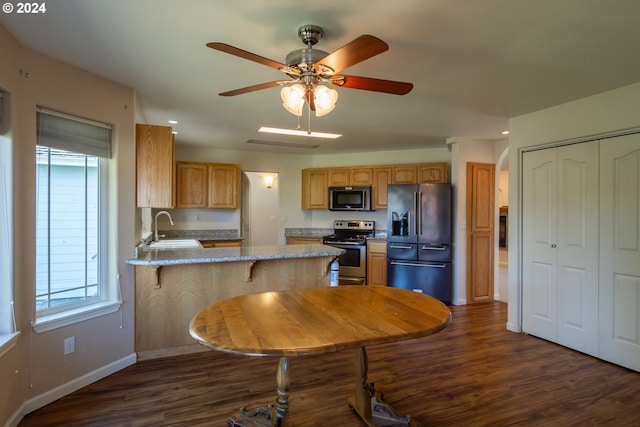 kitchen featuring a kitchen breakfast bar, dark wood-type flooring, kitchen peninsula, sink, and appliances with stainless steel finishes