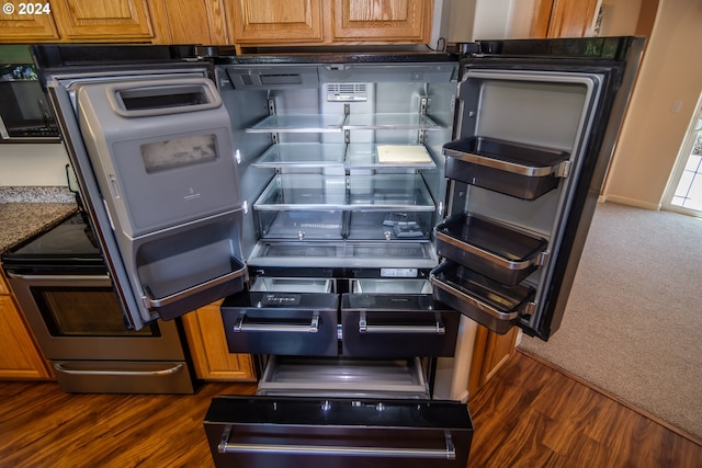 room details with refrigerator, stainless steel electric range, dark hardwood / wood-style floors, and dark stone countertops