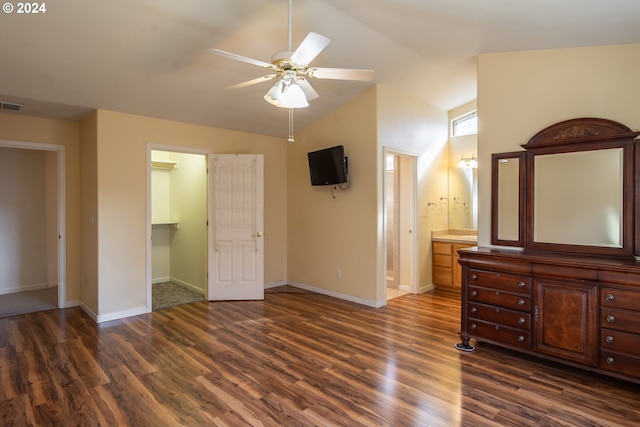 unfurnished bedroom with a closet, dark wood-type flooring, a walk in closet, vaulted ceiling, and ceiling fan