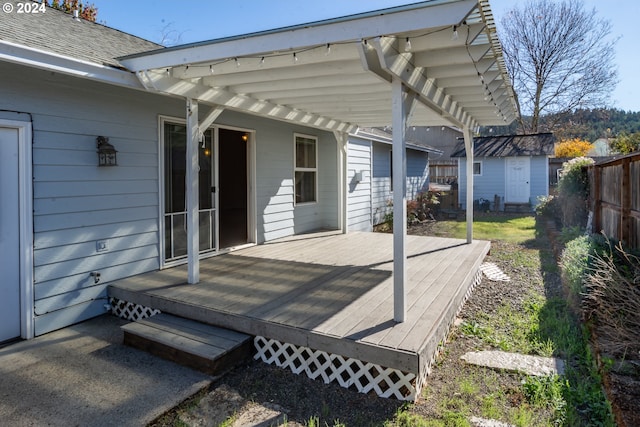 view of patio featuring a wooden deck, a storage shed, and a pergola