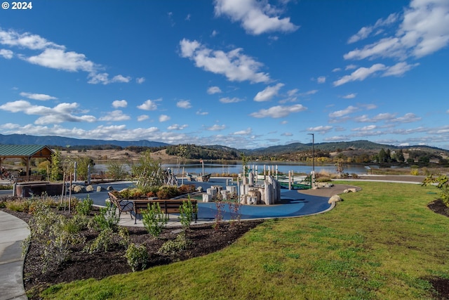 exterior space with a water and mountain view, a lawn, and a boat dock