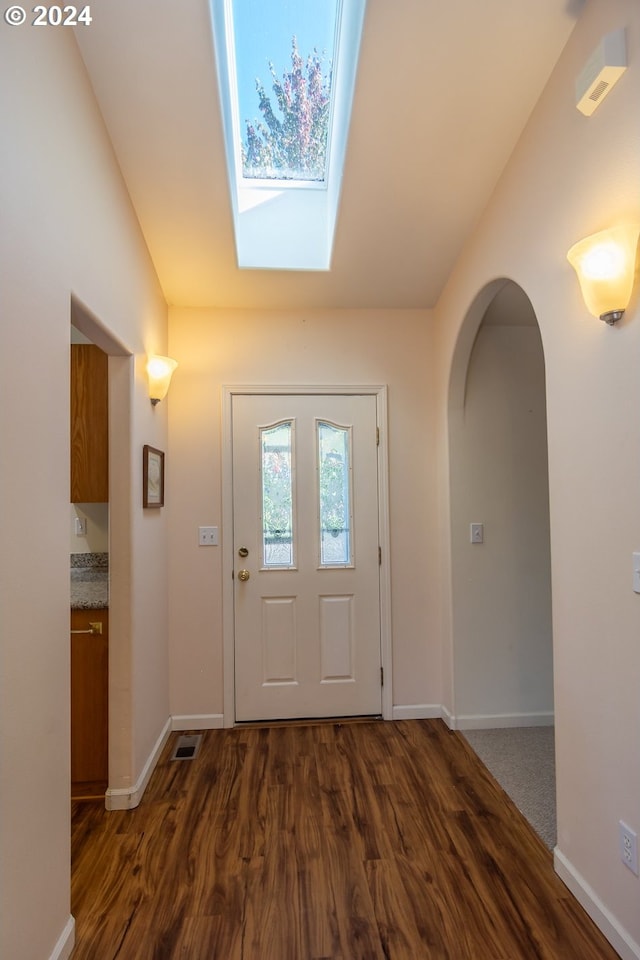 entrance foyer with lofted ceiling with skylight and dark wood-type flooring